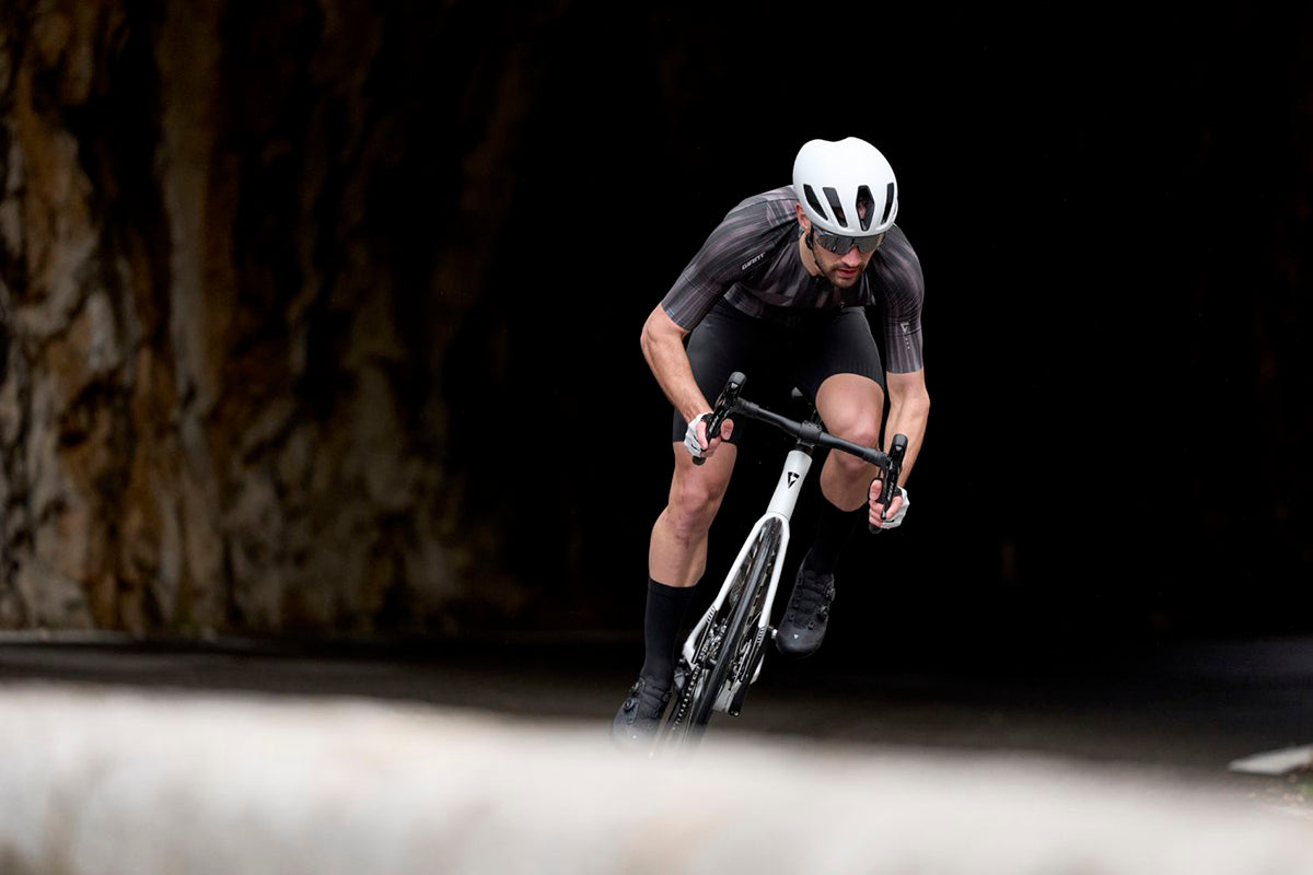 Man wearing white helmet riding a white bike with a black background